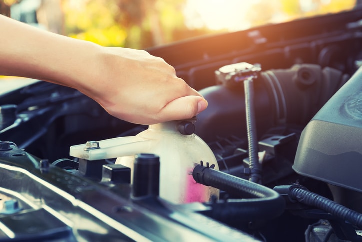 Asian girl's hand checking level of coolant car engine.