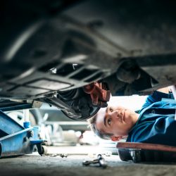 Low angle view of a mechanic working under a vehicle.