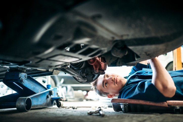 Low angle view of a mechanic working under a vehicle.