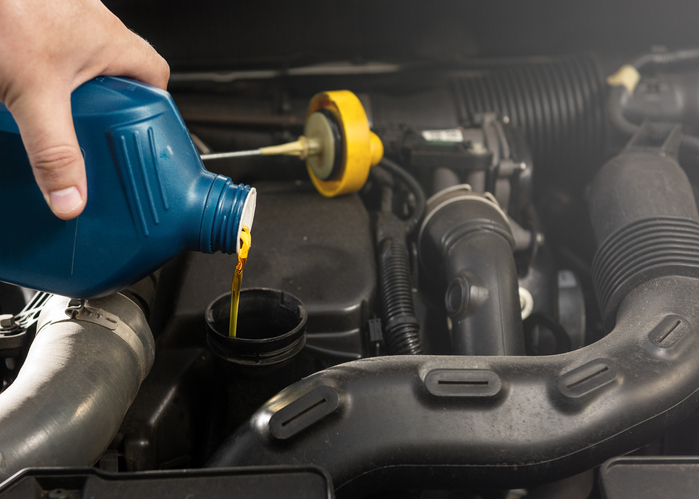 A man changes his car's engine oil
