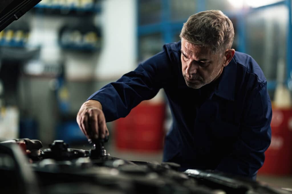 uto mechanic opening radiator cap while repairing car in a repair workshop.