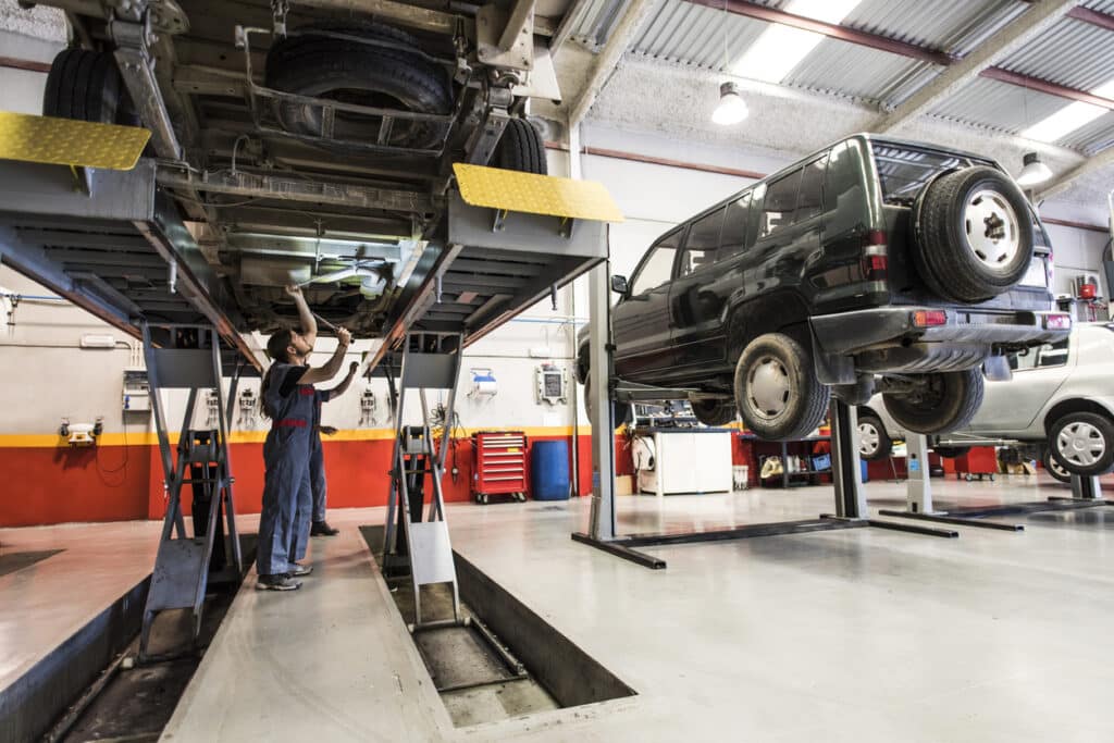 car elevator. Mechanic checks the underside of an industrial car, its chassis and axles on a lifting bench.