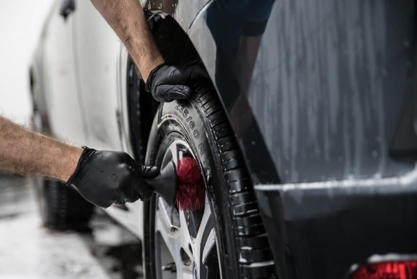 Man cleaning car wheels