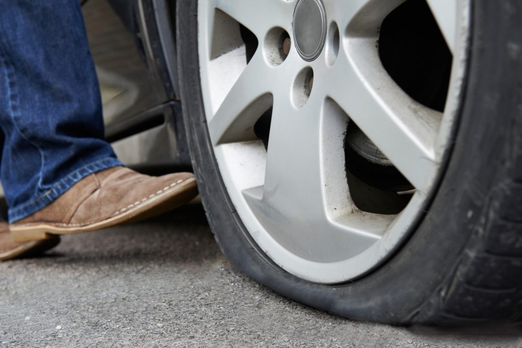 Un automobiliste donne un coup de pied à un pneu crevé sur une voiture