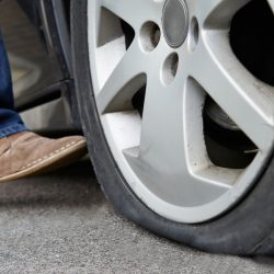 Un automobiliste donne un coup de pied à un pneu crevé sur une voiture