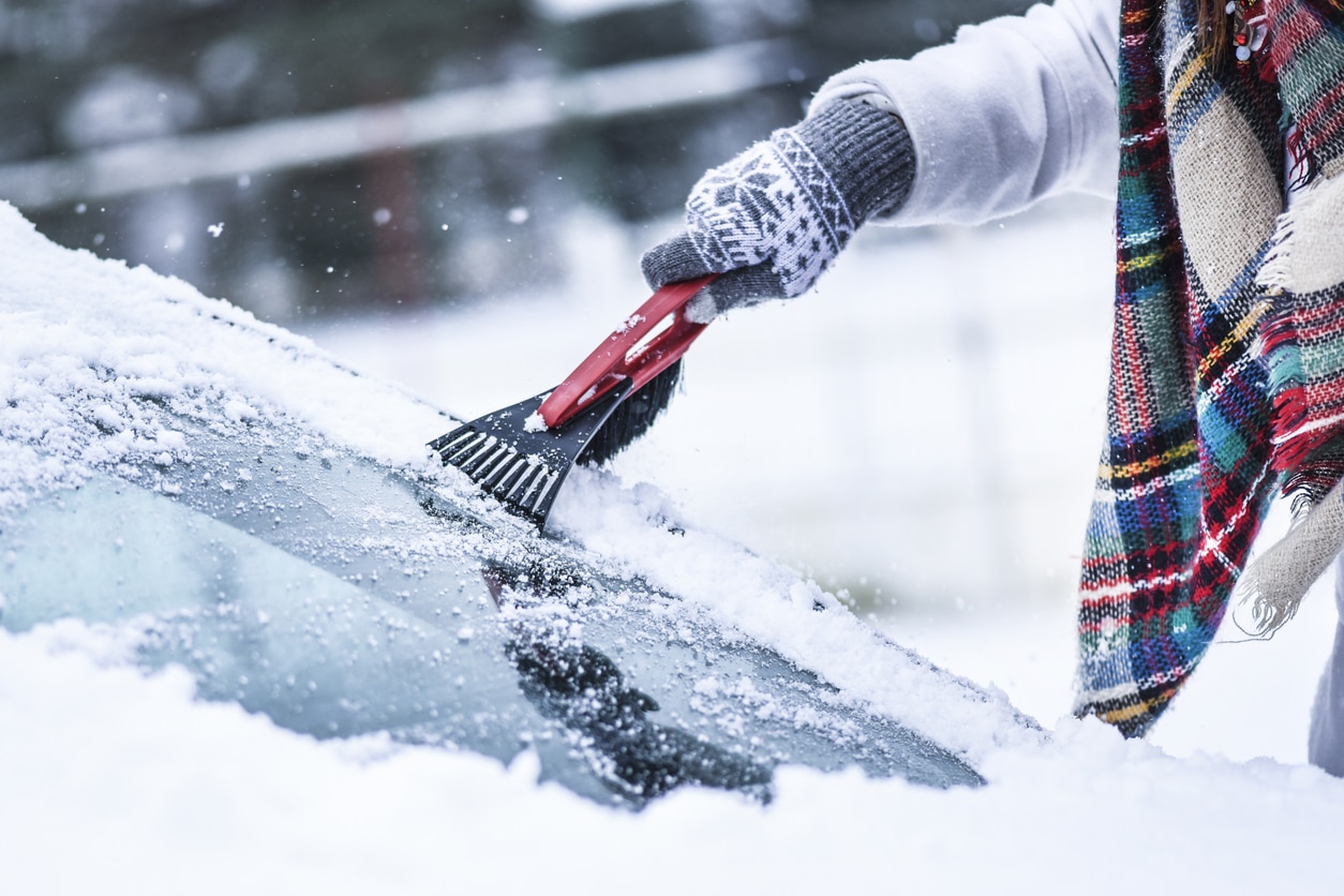 femme nettoie la neige de la voiture