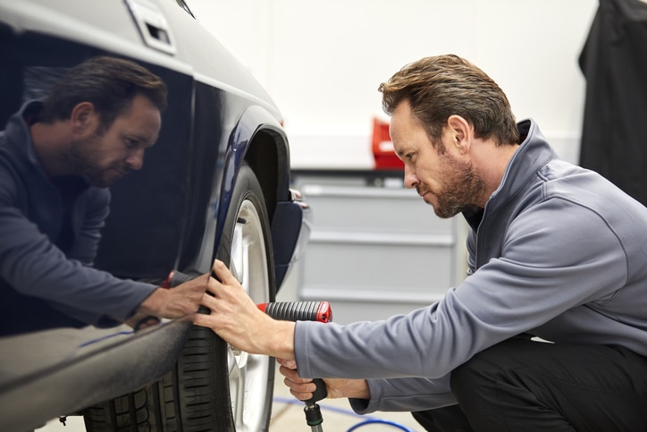 Engineer using electric impact wrench on car wheel