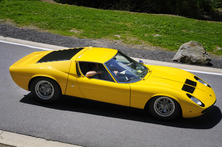 Spa, Belgium - June 29, 2008: Yellow classic Lamborghini Miura S sports car driving on a country road. Two persons are sitting in the car.