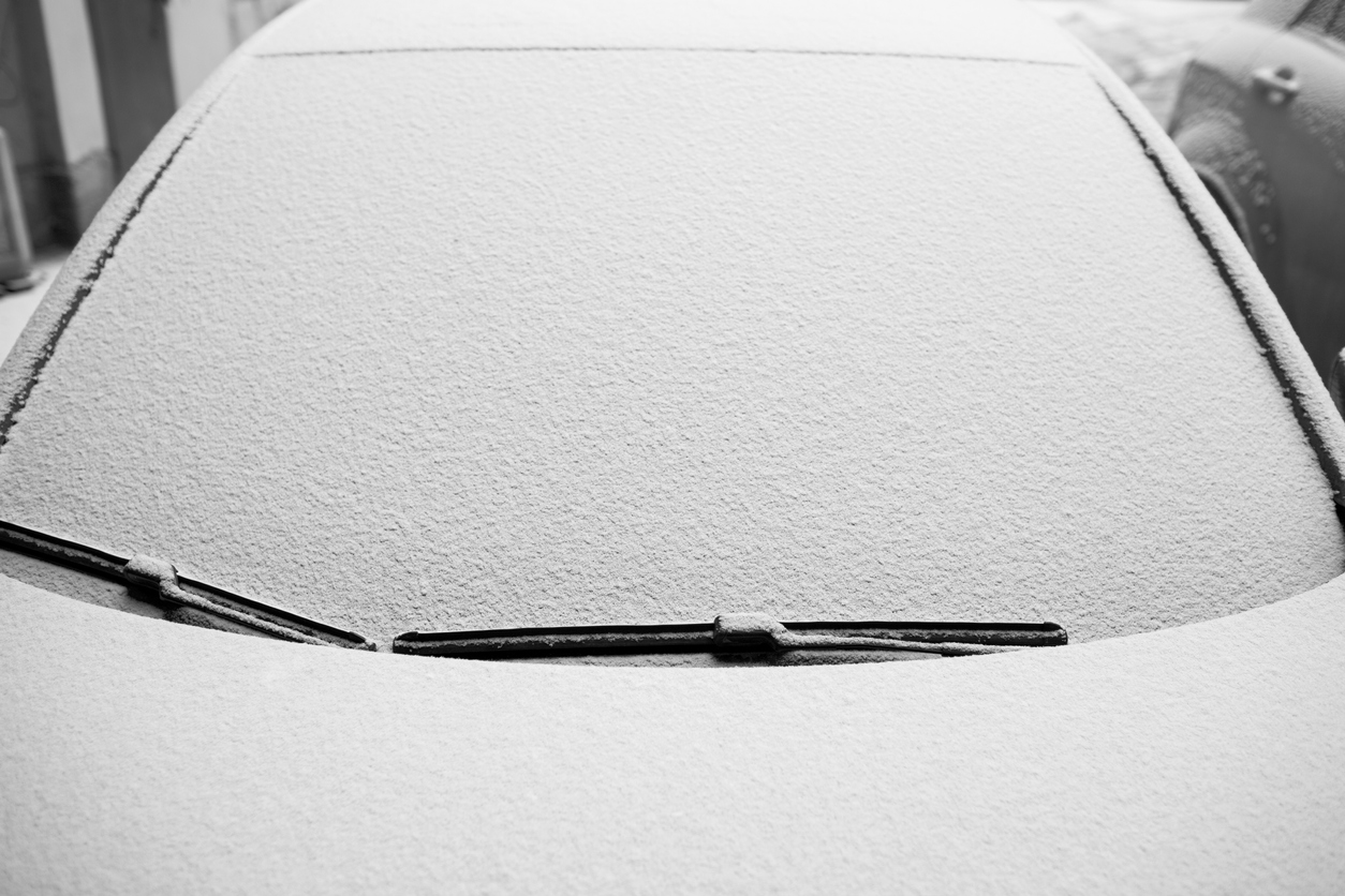 Snow-covered windshield wipers and windshield on the car.