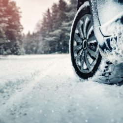 Car tires on winter road covered with snow. Vehicle on snowy way in the morning at snowfall