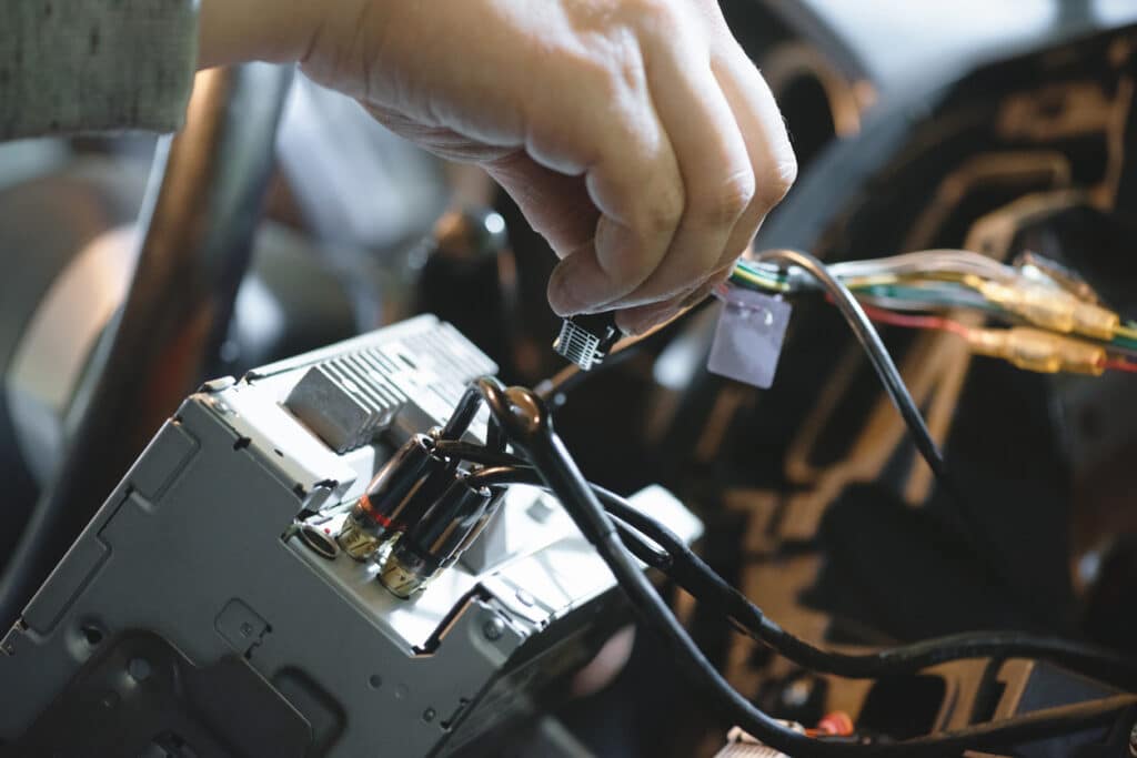 Auto electrician is installing a car radio sound system close up.