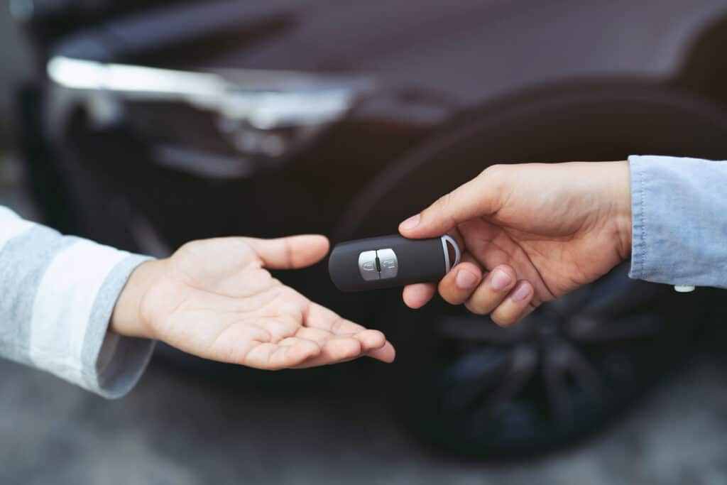 businessman exchange handing over the car keys for to a young women.