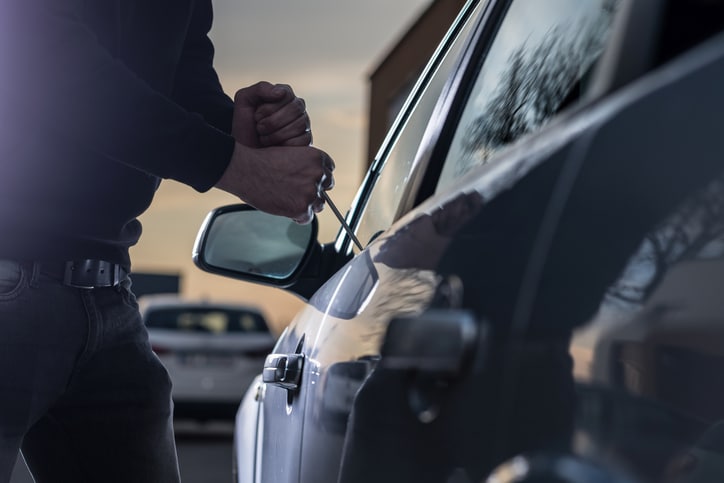 Auto thief in black balaclava trying to break into car