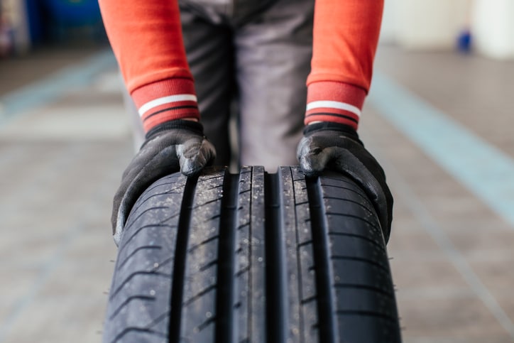 Closeup Shot of a Mechanic's Hands Holding a Black Tire