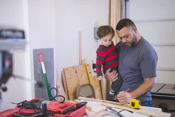 Dad and young son work construction project together in garage workshop