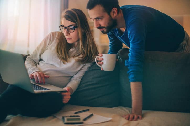 Couple sitting in their living room and checking their finances on the computer