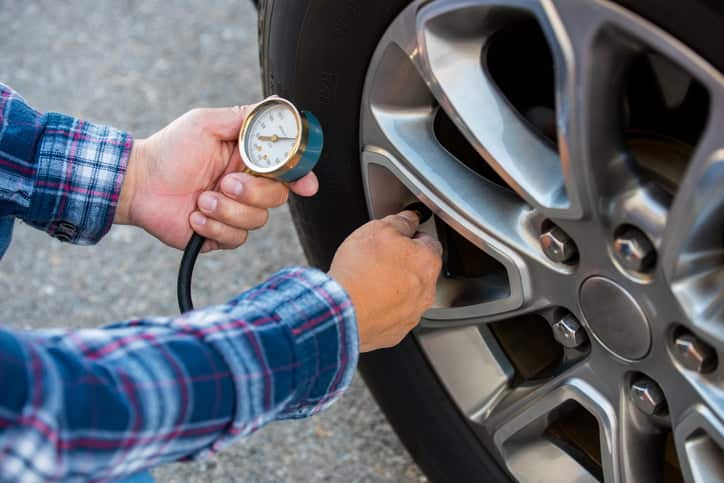 Man Checking Tyre Pressure While Maintaining Tyres