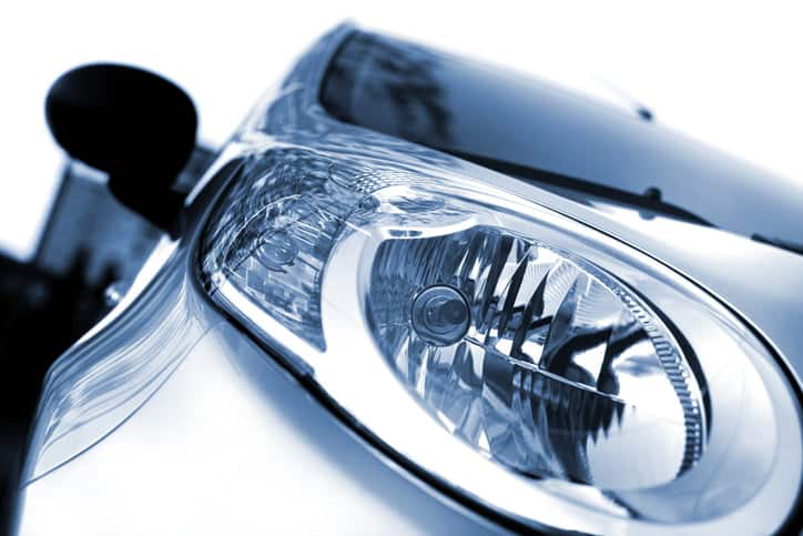 Close up of the head lights of a new car. The color of the car is silver metallic, blue. The background is white. Front view, left wing. photographed with a 50mm prime lens and full frame camera.modern car-light, isolated on white, toned image