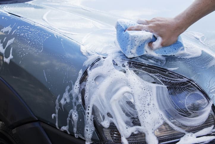 the turquoise car is washing in soap suds