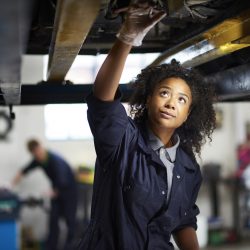 Women mechanic working under a car