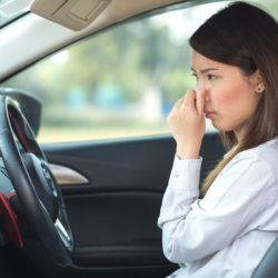 woman holding her nose in the car
