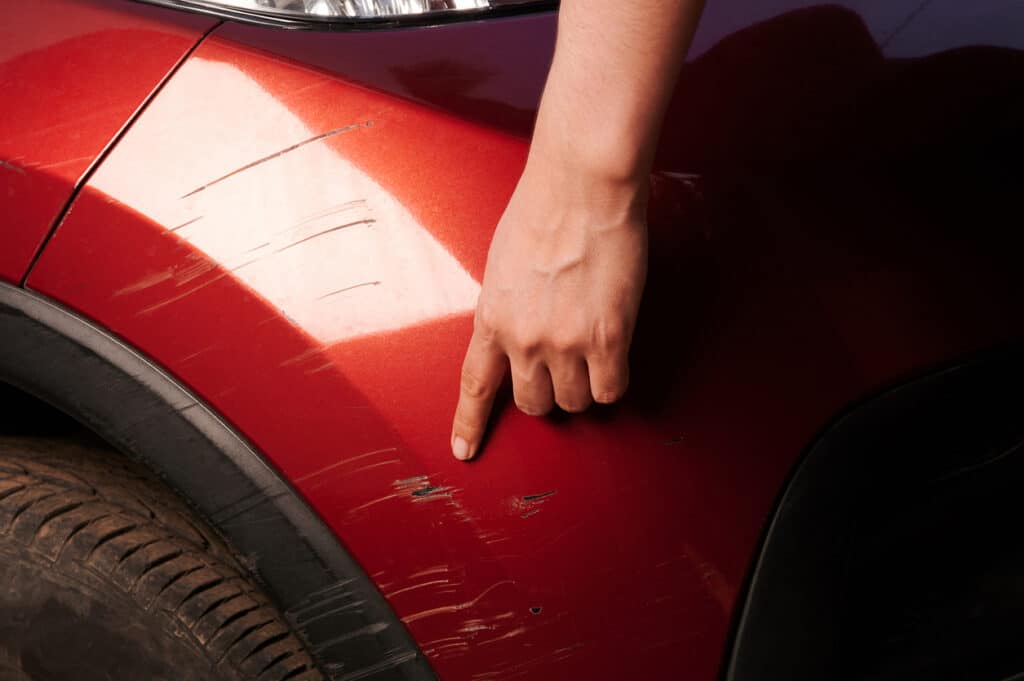 car with scratched red paint above wheel