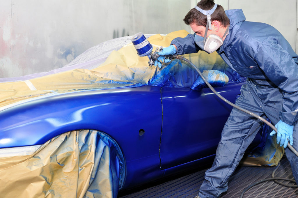 Man painting a blue car.
