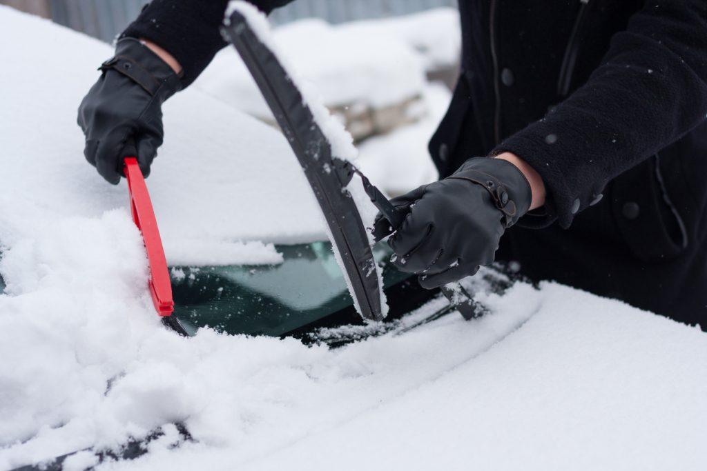 Driver clean his car after snowfall