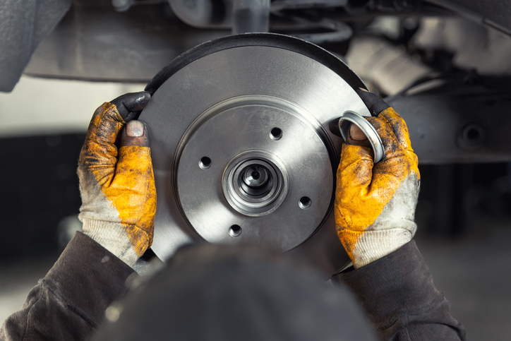 mechanic installing car brake steel rotor disk