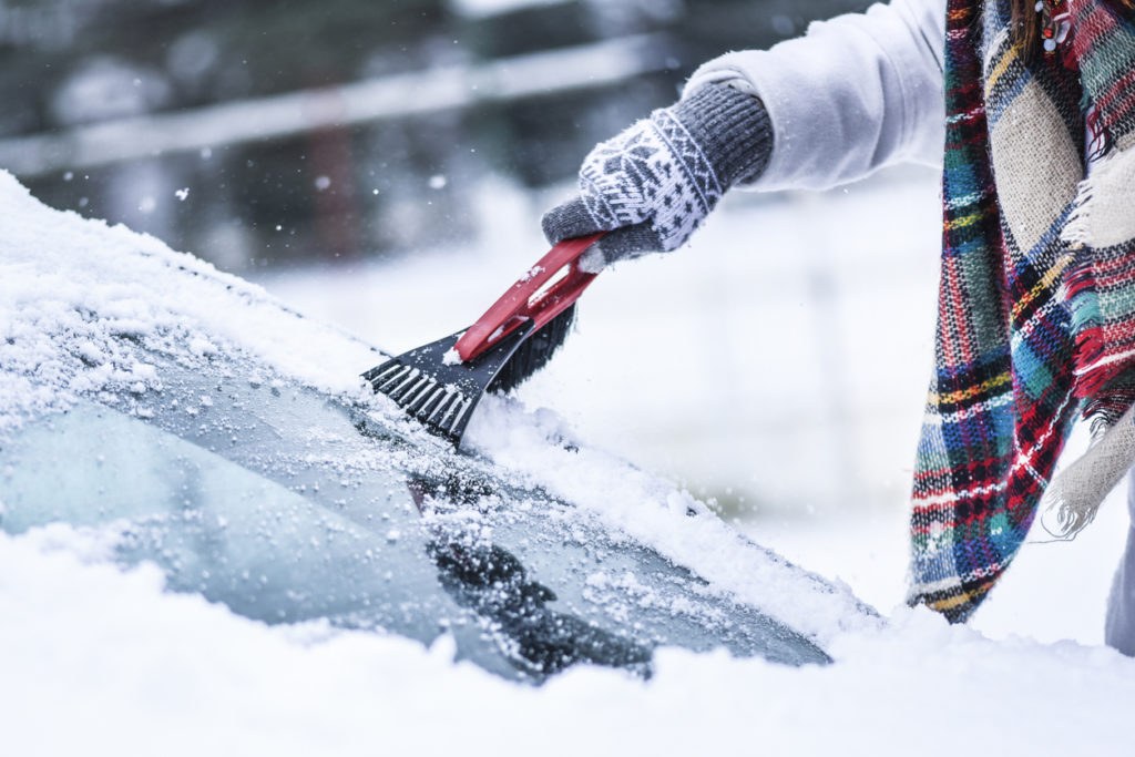 Woman cleaning snow from windshield