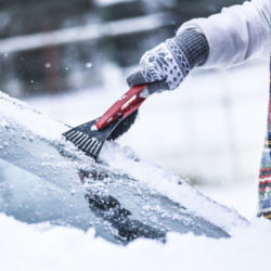 Woman cleaning snow from windshield