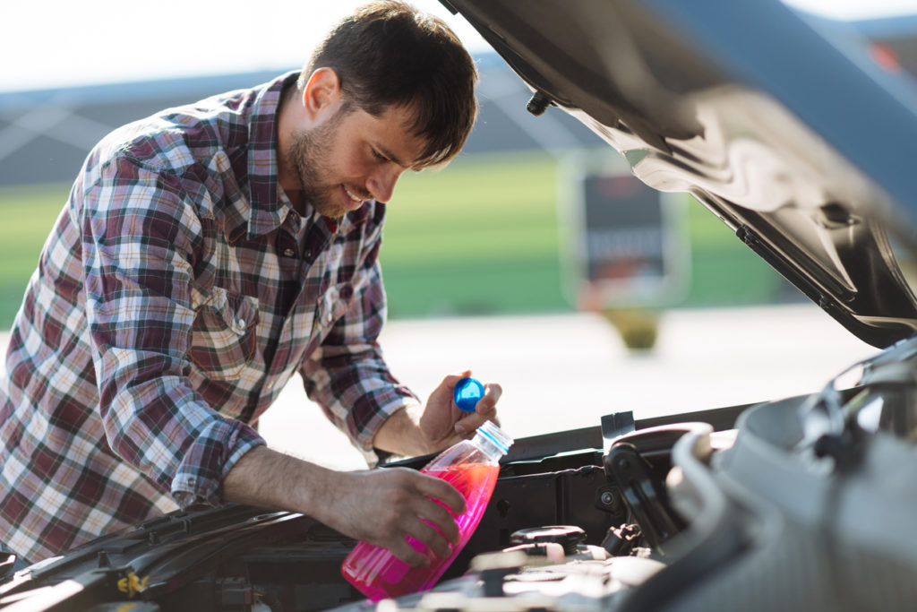 Man pouring antifreeze or coolant in car