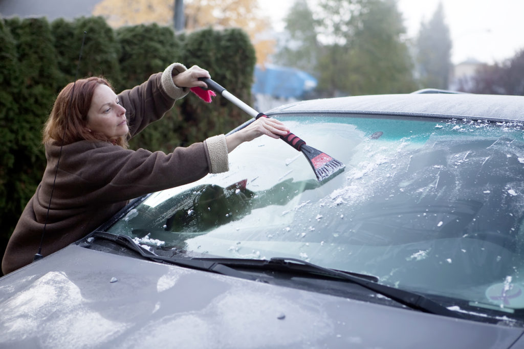 Woman clearing frost from her van window.