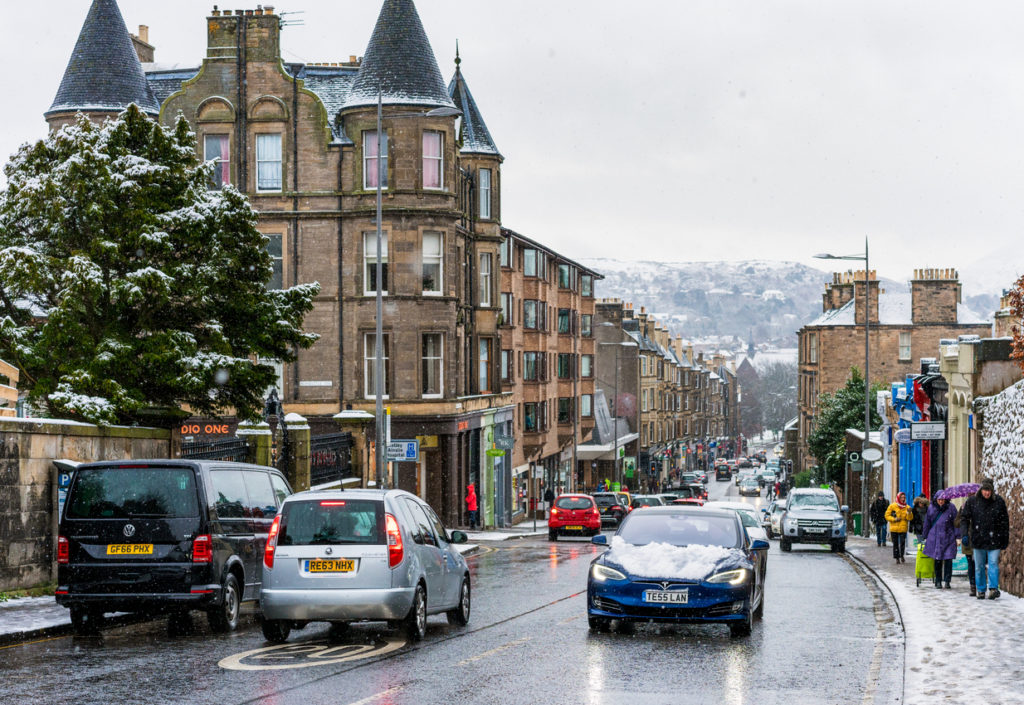 Edinburgh, Scotland - A Tesla and other cars on the road, and pedestrians on the pavement during snowy weather in the Scottish capital.