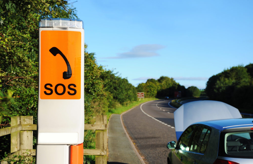 A SOS emergency call box of the new type currently being rolled out across the north of England. This particular box is situated in a lay-by in Cumbria with a disabled motor vehicle adjacent with the bonnet open. Taken early in the morning on a bright summers day.