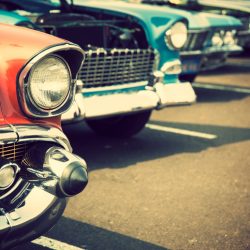 Photograph of classic cars with close-up on headlights parked in a row.