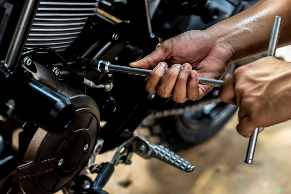 People holding hand are repairing a motorcycle Use a wrench and a screwdriver to work.