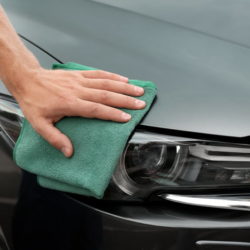 Man washing car headlight with rag, closeup