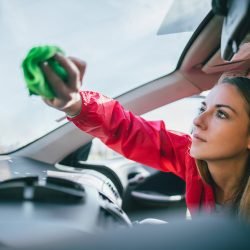 Young woman washing car and cleaning car windows