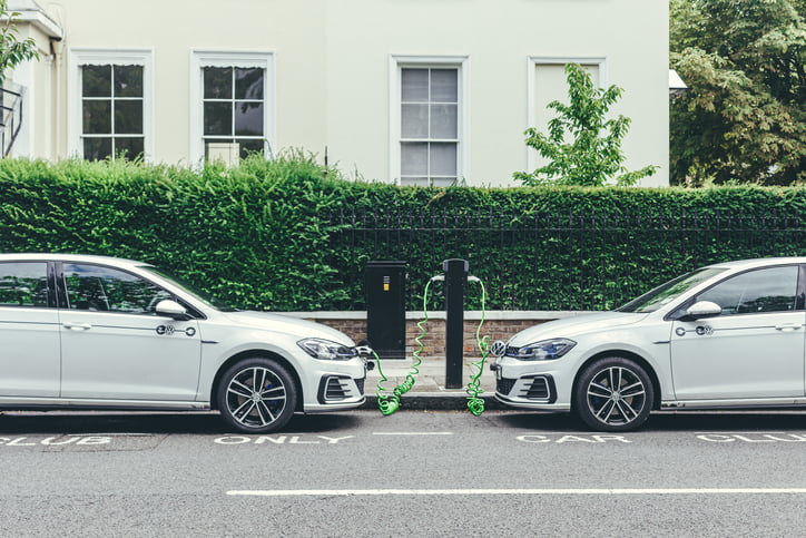 London/UK-30/07/18: two white Volkswagen Golf GTE cars charging at a charging point on a street in London. The Golf GTE is a plug-in hybrid version of the Golf hatchback