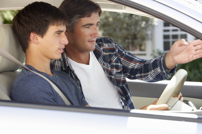 young woman takes driving lesson from his father