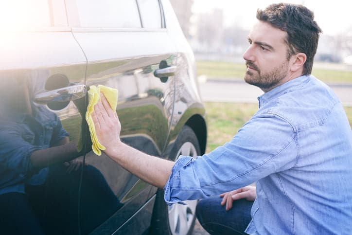 Man taking care and cleaning his new car with sponge
