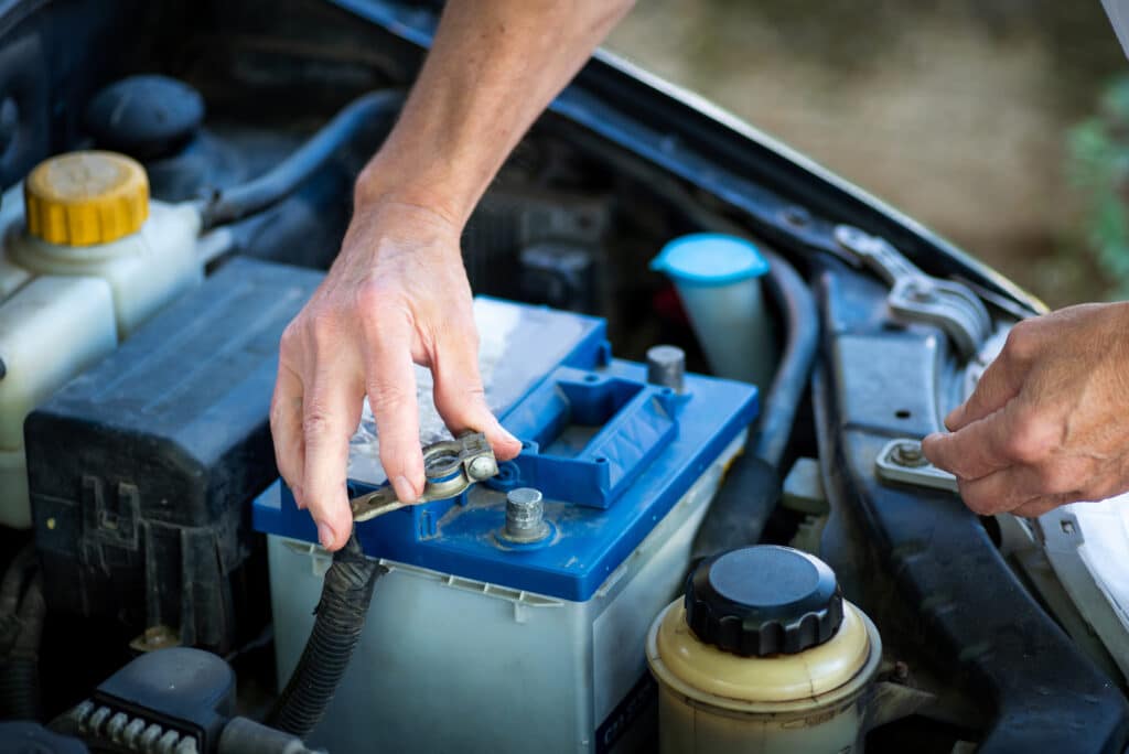 Cropped hands attaching car battery to the cars system